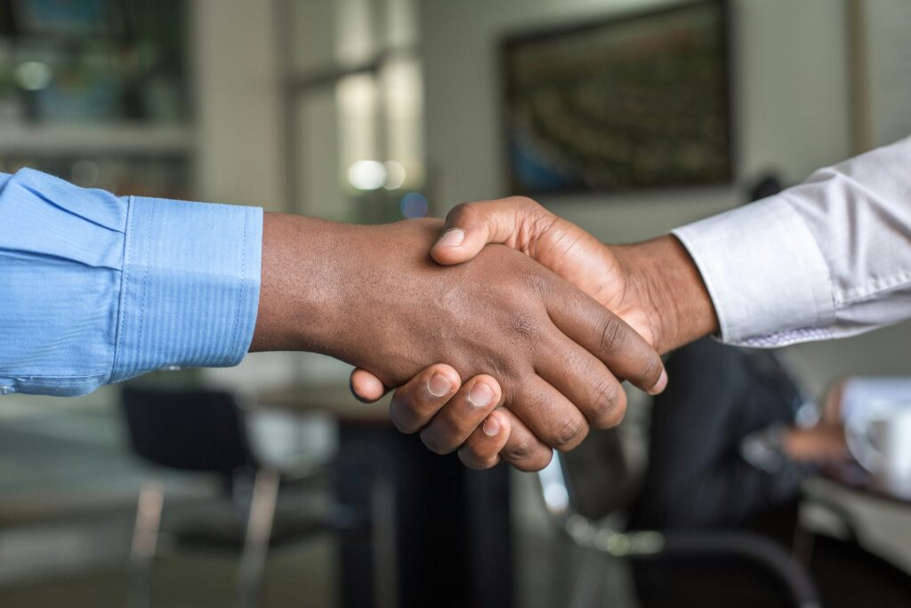 A photo of two people shaking hands in a business building. 